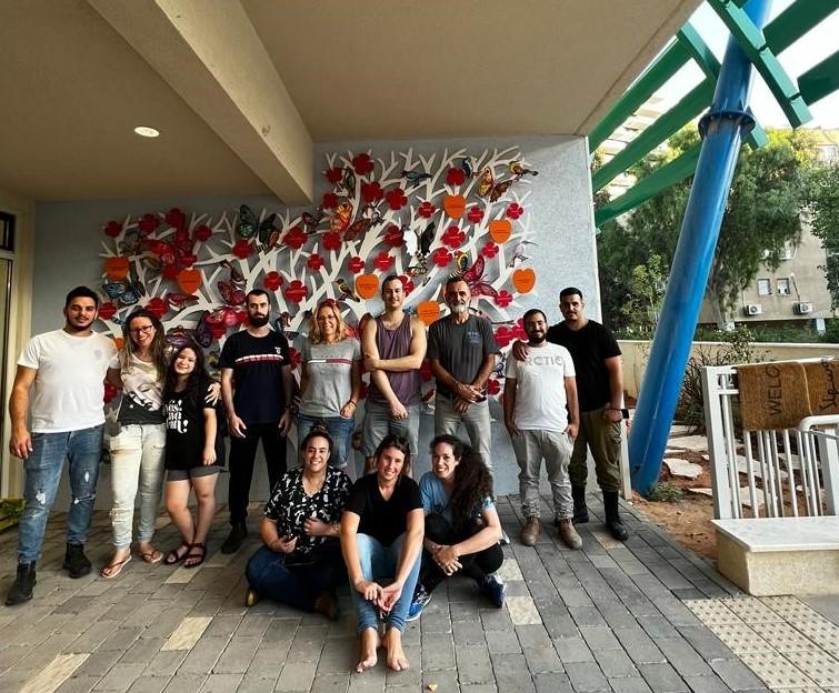 Leidos Israel team poses for a picture in front of a wall painted with flowers