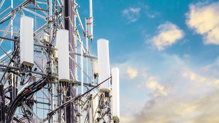 close up of a 5G tower against a blue, partly cloudy sky