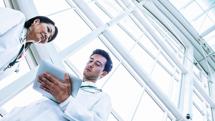 Male and female doctor look at medical records on a tablet