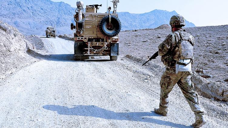 solider following behind military vehicle