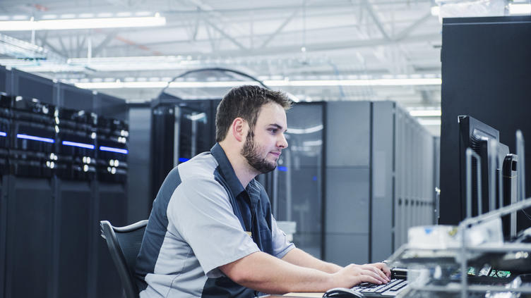 Caucasian technician using computer in server room