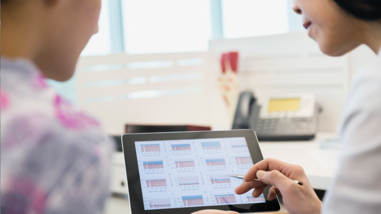 Female doctor discusses chart data with patient via tablet