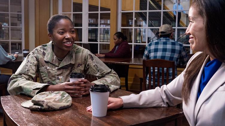 Two women, one in military uniform, sharing a coffee