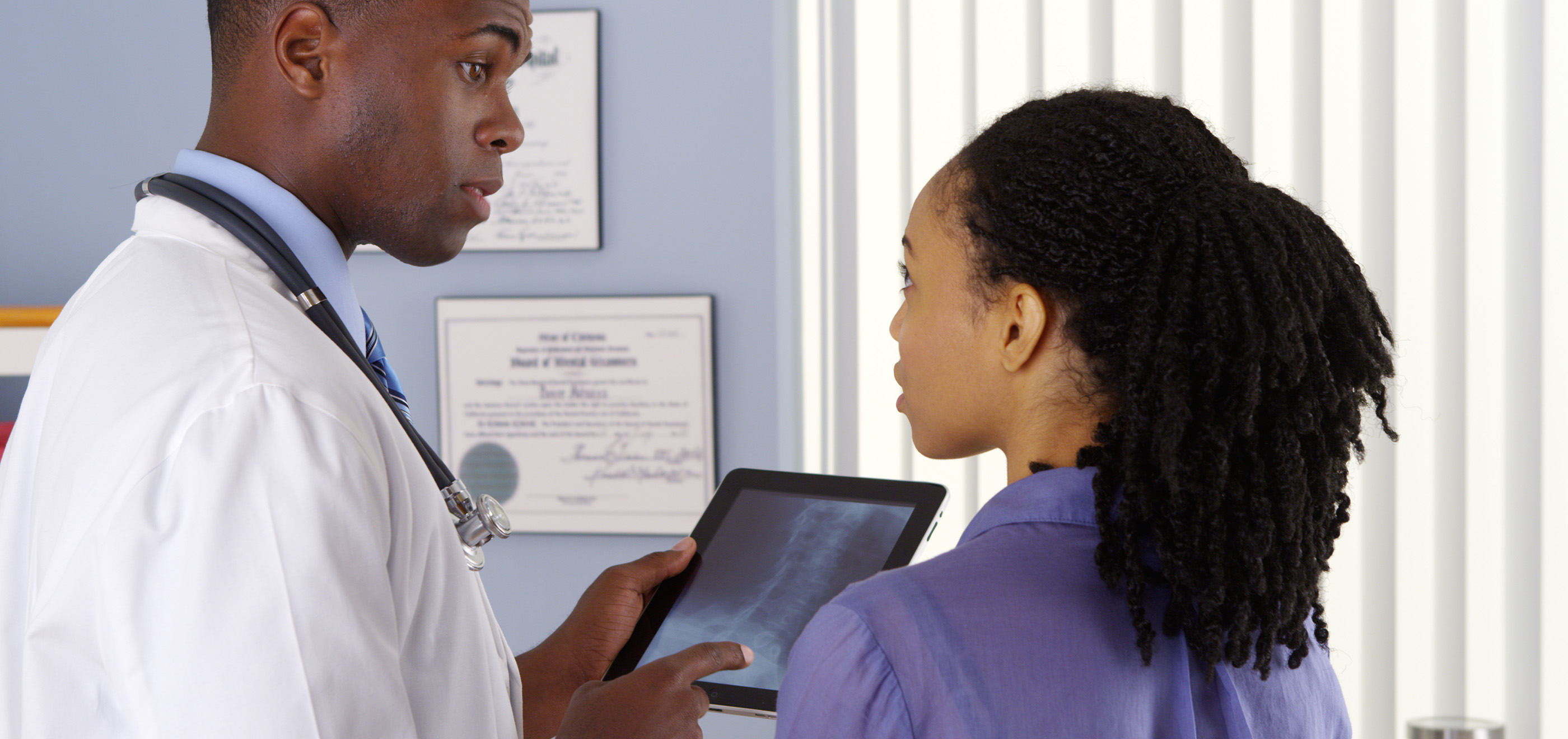 male doctor talking with nurse reviewing xrays over tablet