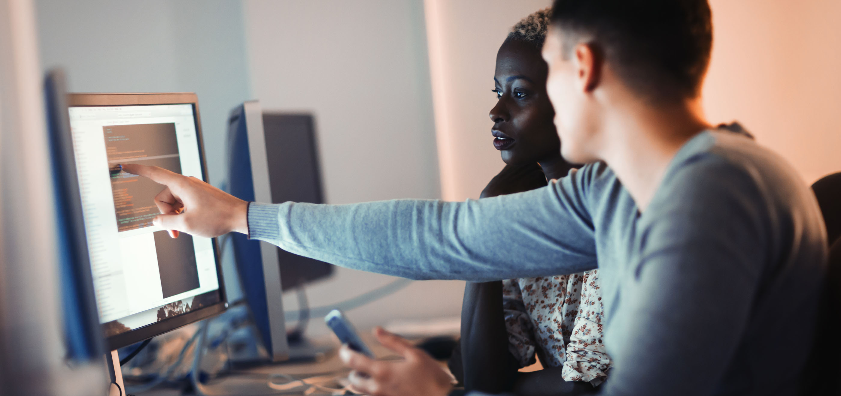 two coworkers collabrating at a computer monitor