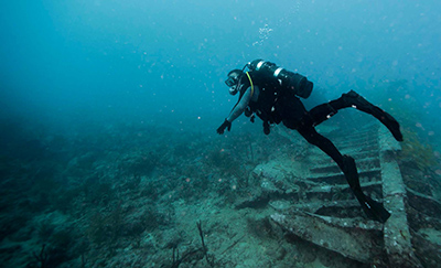 ocean diver surveying debris on ocean floor