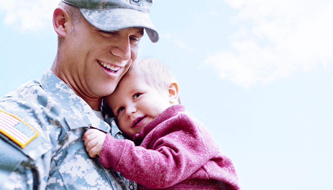man in military uniform holding baby boy