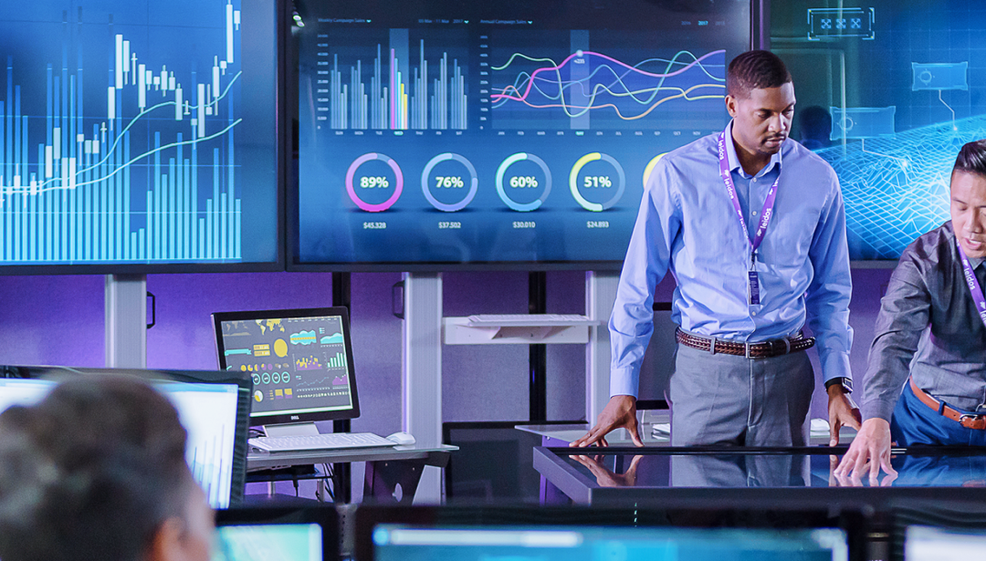 two coworkers collaborating over a large screen with data
