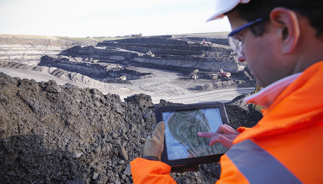Man in safety vest looking at tablet with location information on it