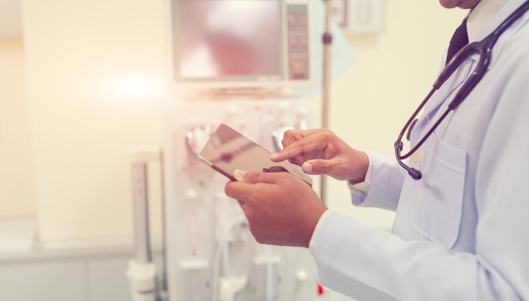 doctor with stethoscope around neck holding tablet