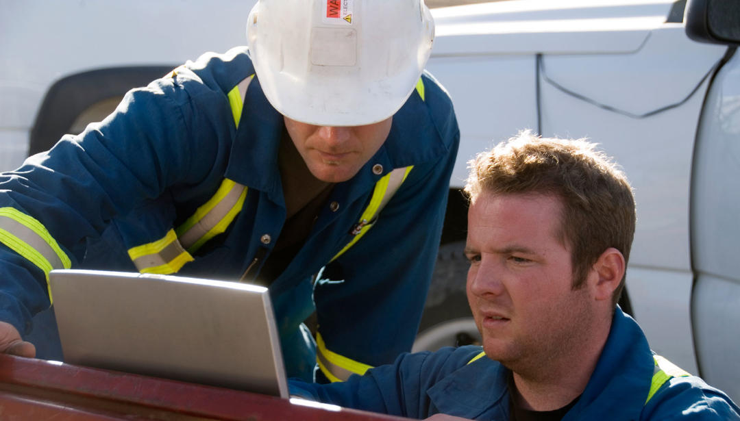 two engineers looking at a screen at an outdoor work site