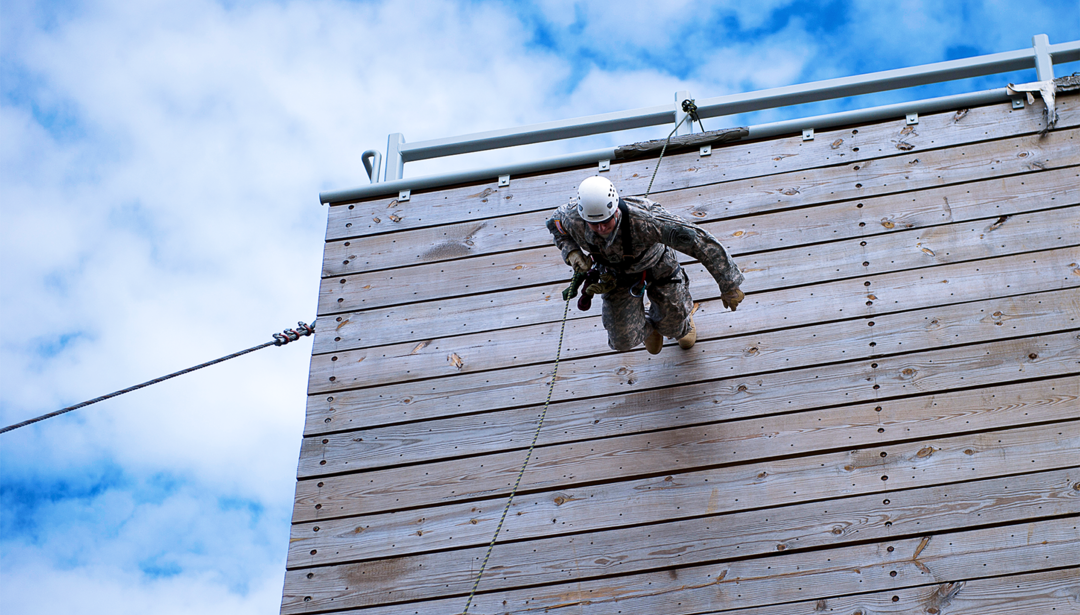 Military person scaling down wall 