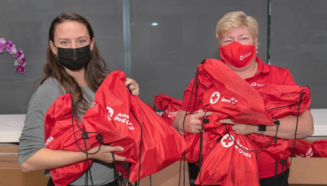 Photo of two women holidng red cross supply bags