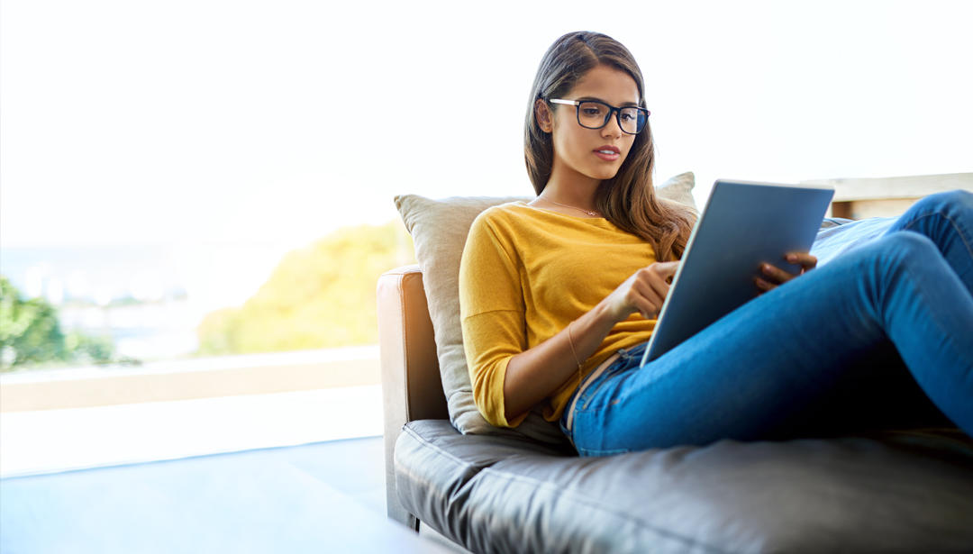 Women laying on couch with tablet.