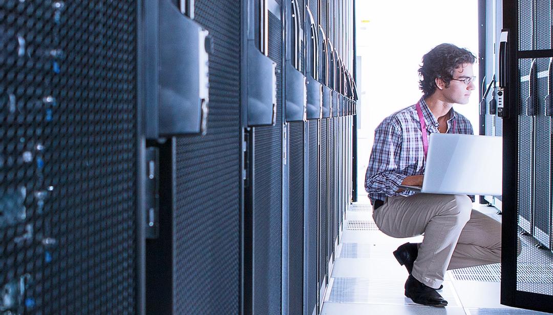 man in server room with laptop