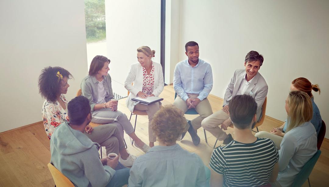 group counseling session with ten people sitting in a circle in chairs