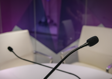 Microphones on a table in front of a purple background