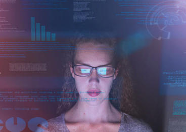 Woman looking at computer screen reflection in glasses