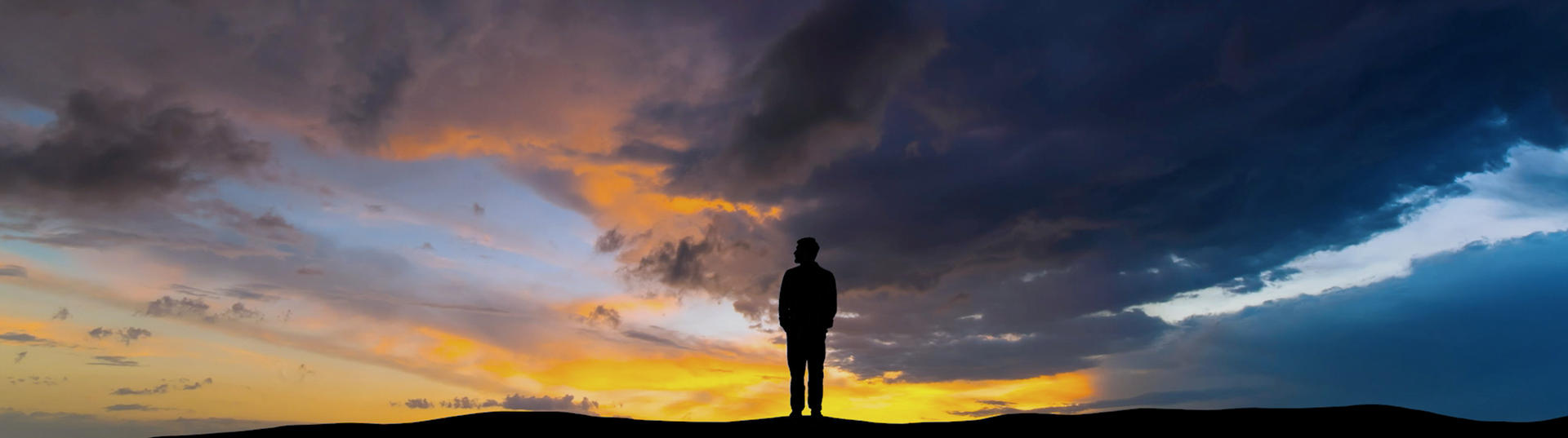 Silhouette standing in front of a sunset