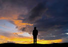 Silhouette standing in front of a sunset sky