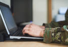 man in military uniform typing on laptop