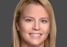 Trisha Eknes headshot in front of a gray background