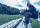 John Hindman sitting on bleachers holding a soccer ball