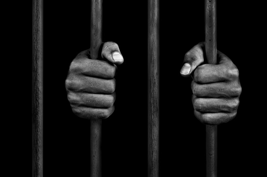 The hands of a prisoner behind bars