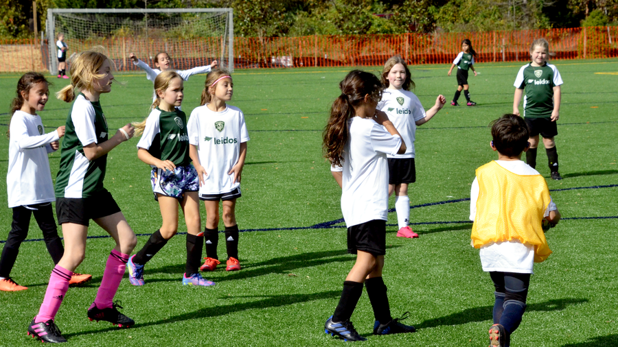 young girls playing soccer wearing jerseys with Leidos logo