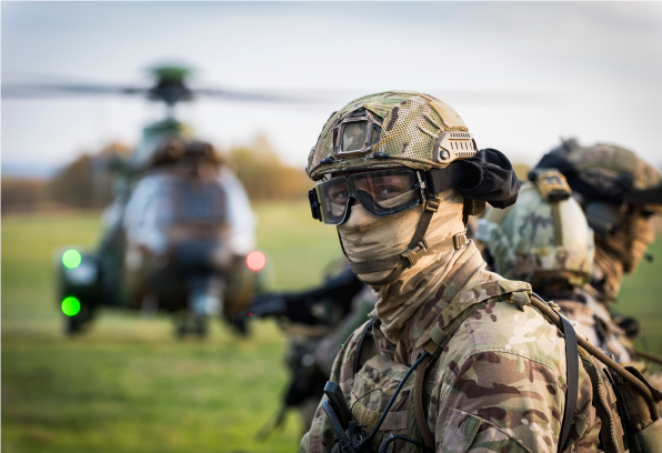 UK solider in uniform in the field with helicopter in the background