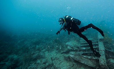 ocean diver surveying debris on ocean floor