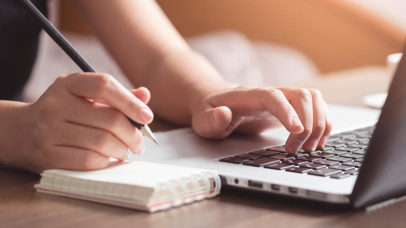 writing in notebook and using laptop