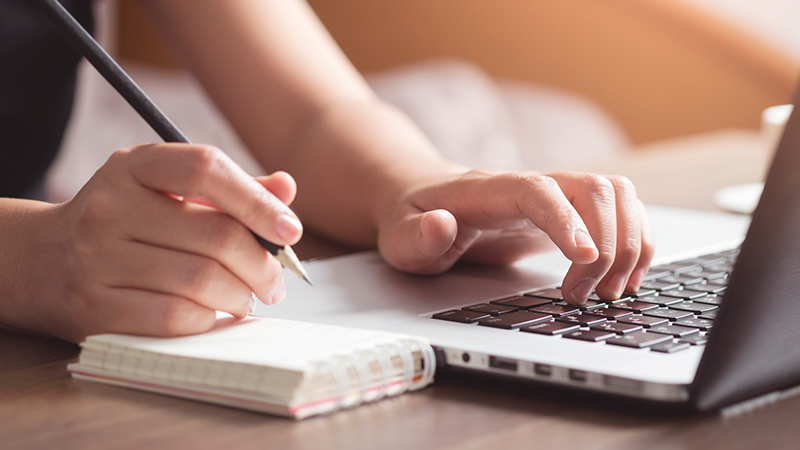 writing in notebook and using laptop