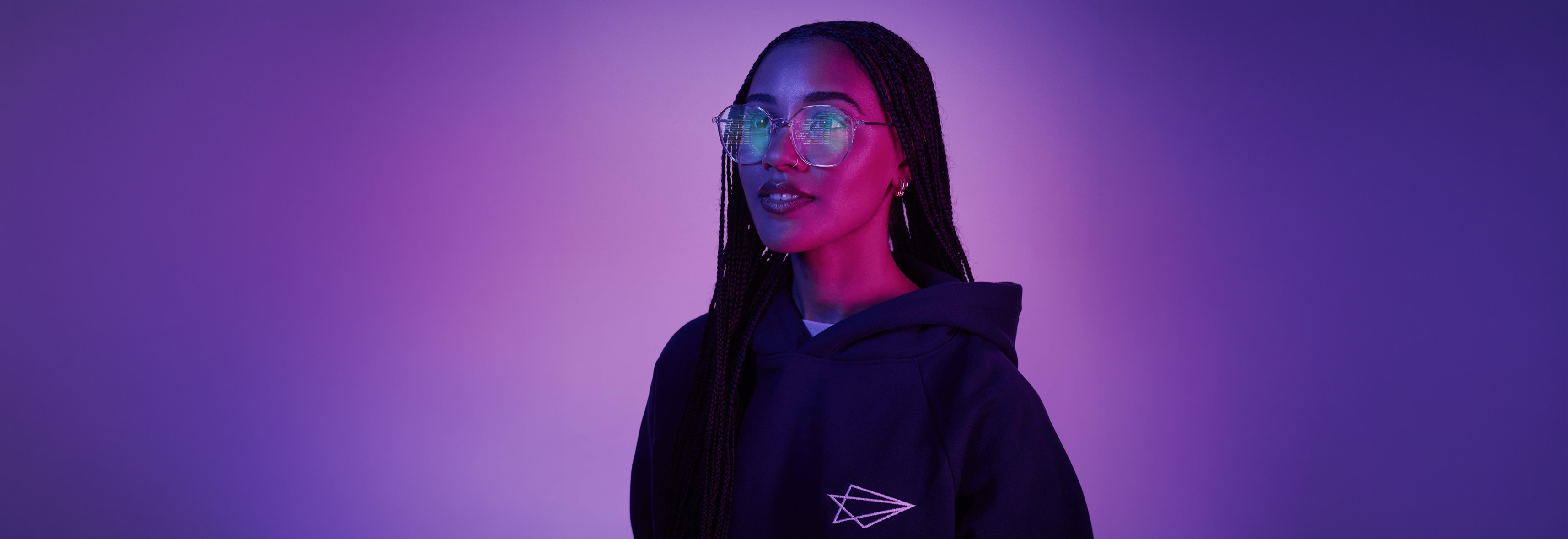 Woman with larger glasses reflection shows computer code on monitor