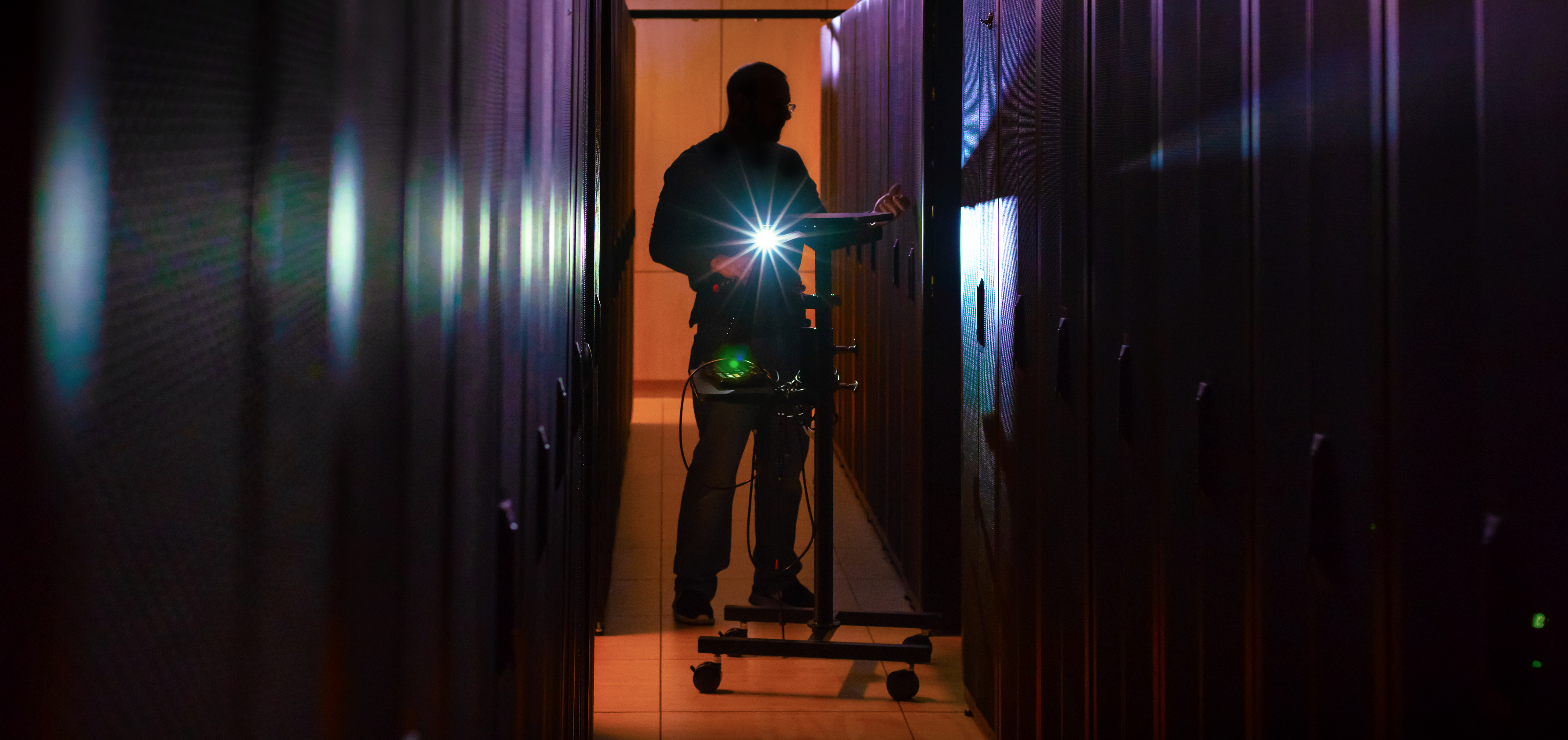 A man standing in a server room holding a torch