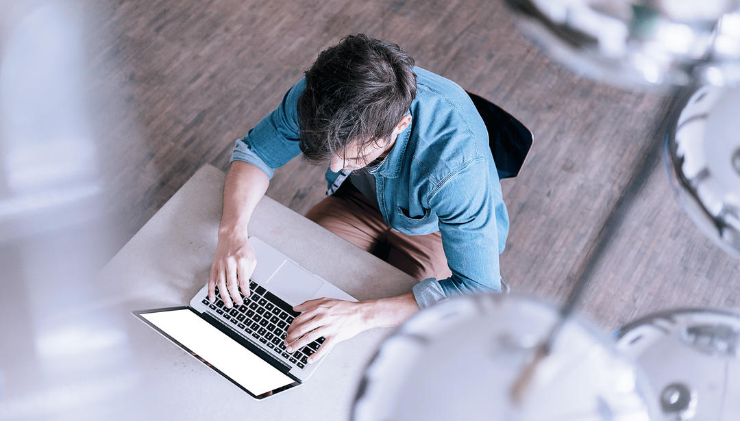 Man sitting at desk on laptop from bird's eye view