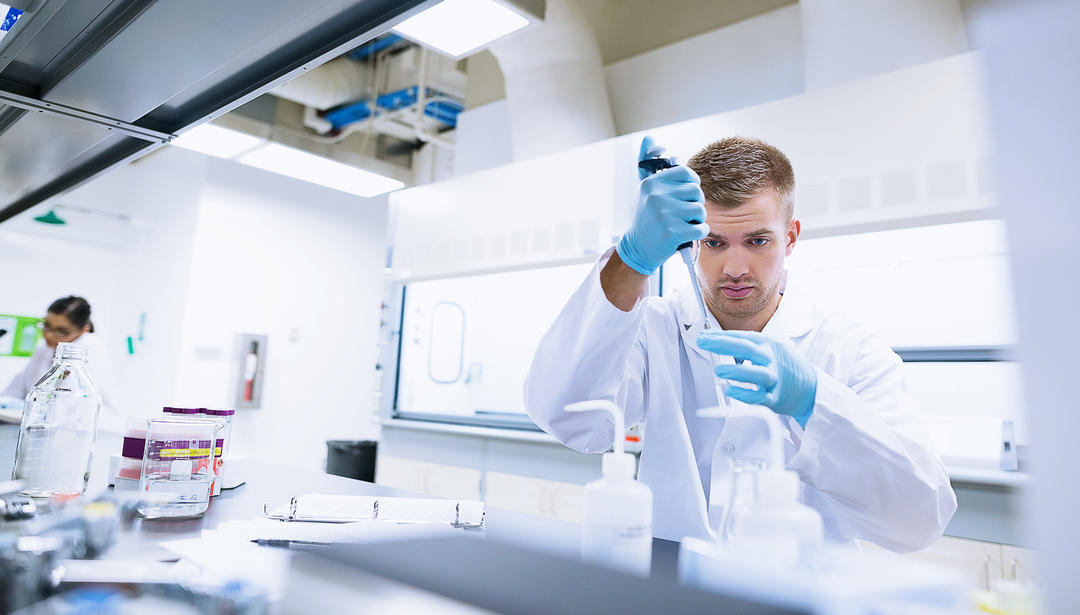 Man in lab with medical dropper adding to sample