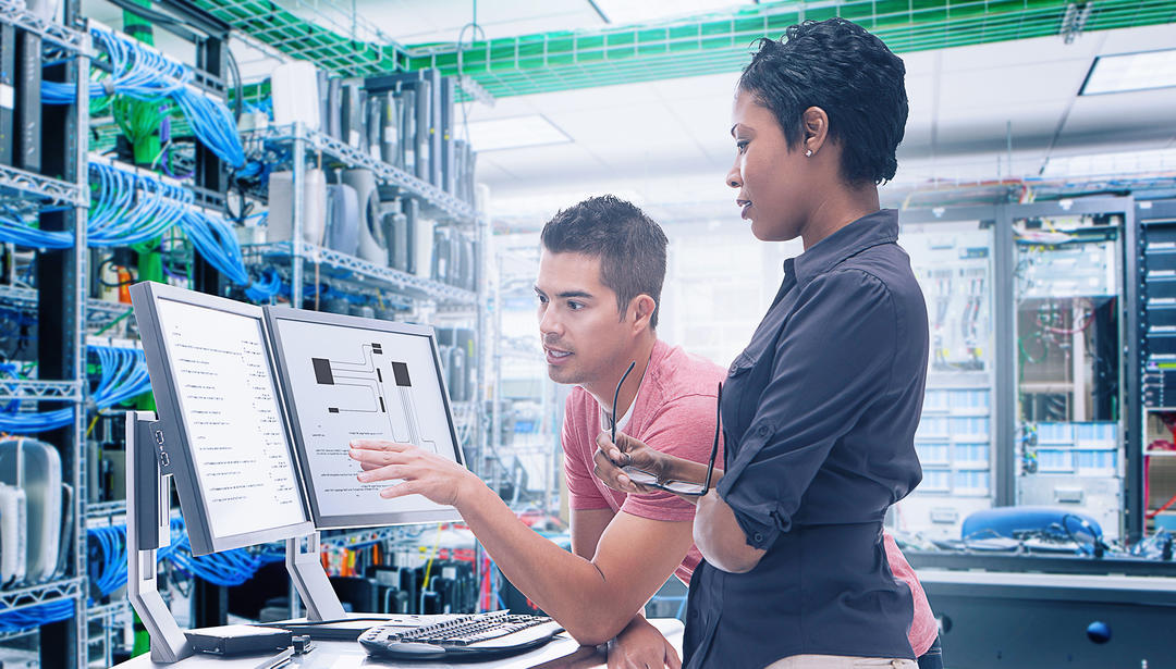 two coworkers in a data center working on computer screen