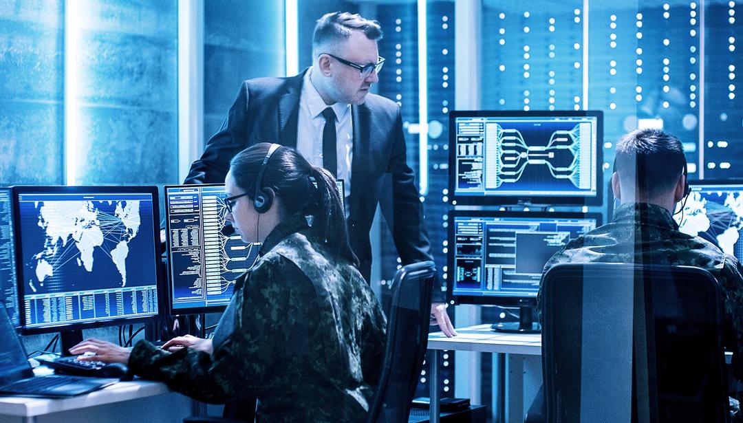 coworkers in uniforms sitting at monitors working in data studio