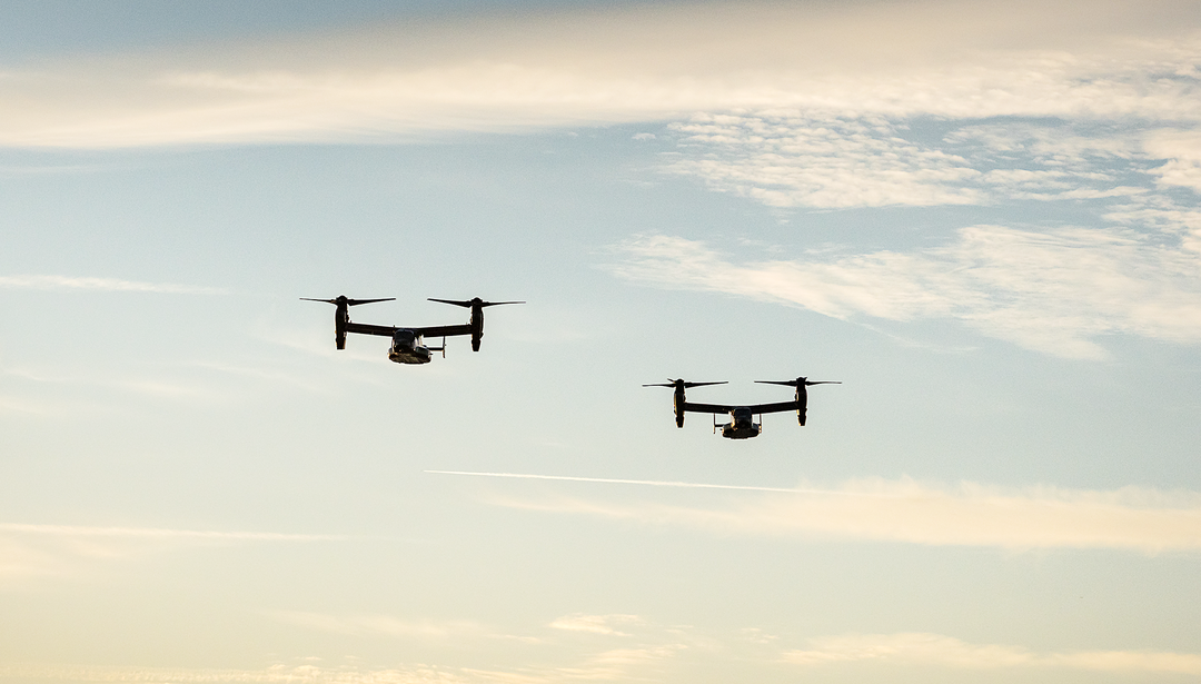 two drones flying in the sky with clouds behind them