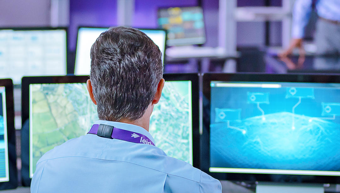 view from behind a man looking at multiple monitors