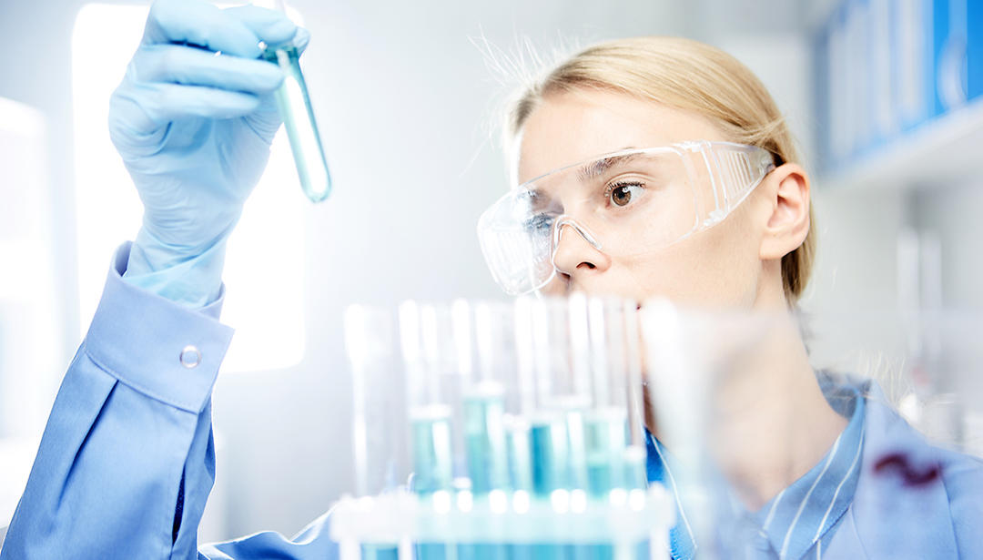 Scientist in lab looking at a test tube