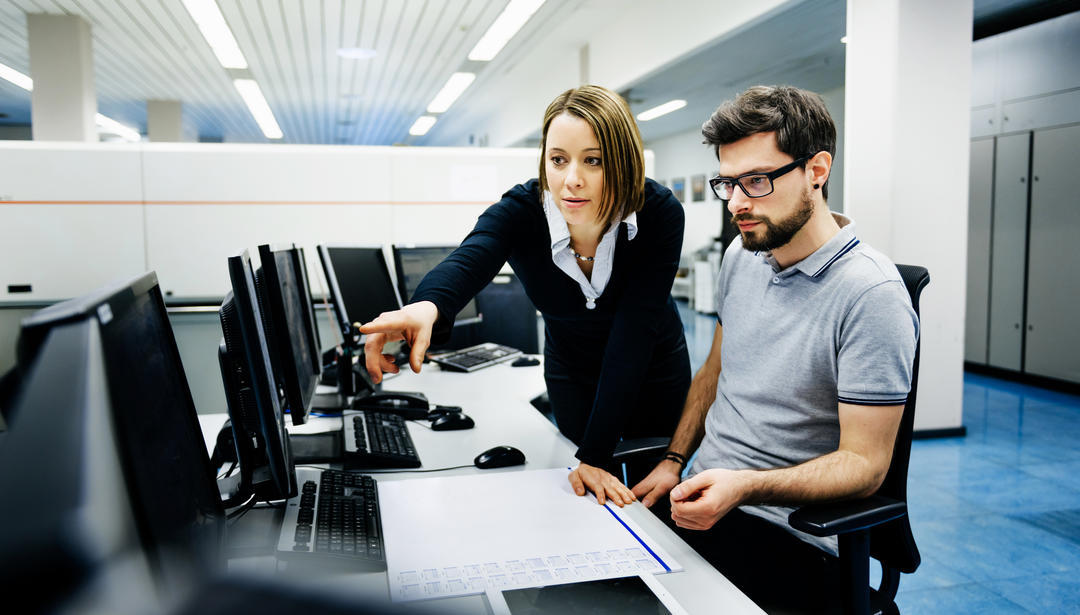 two people looking at computer, one person pointing at screen