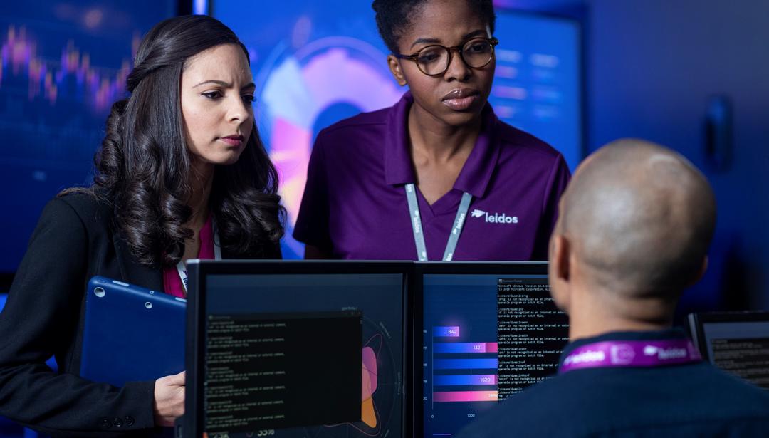 three Leidos employees meeting around computer