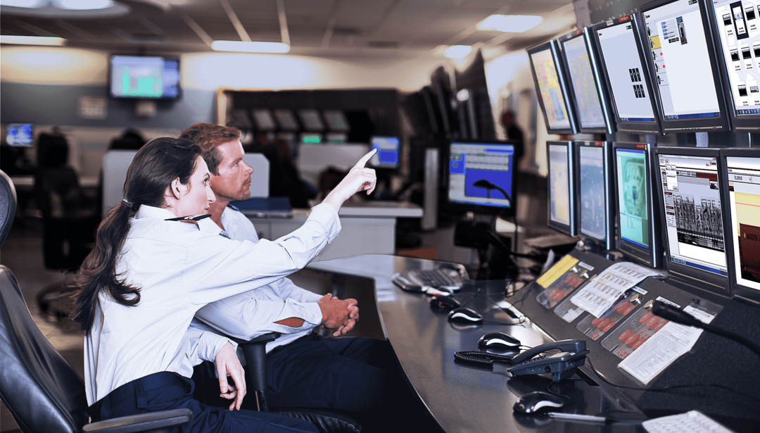 man and woman sitting at multiple screens reviewing information