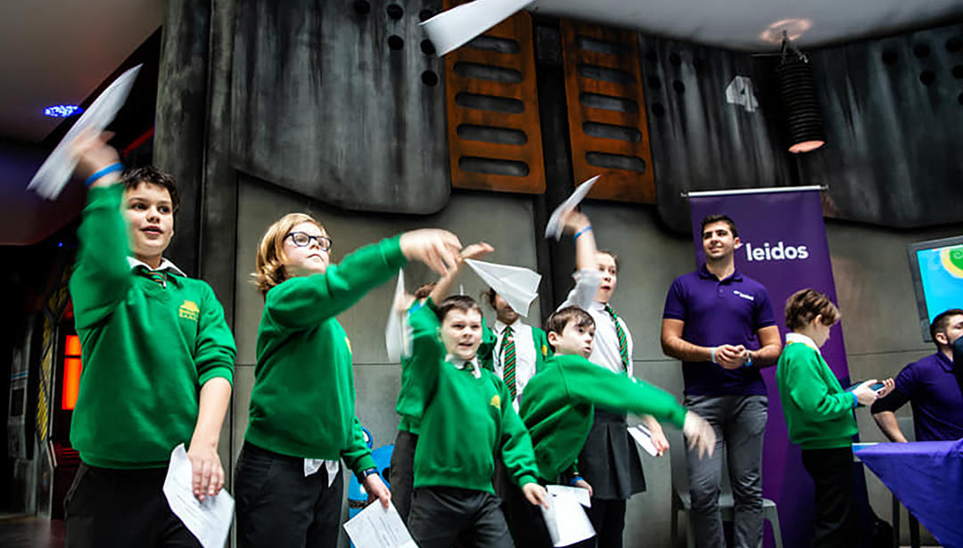 school children throwing paper airplanes 