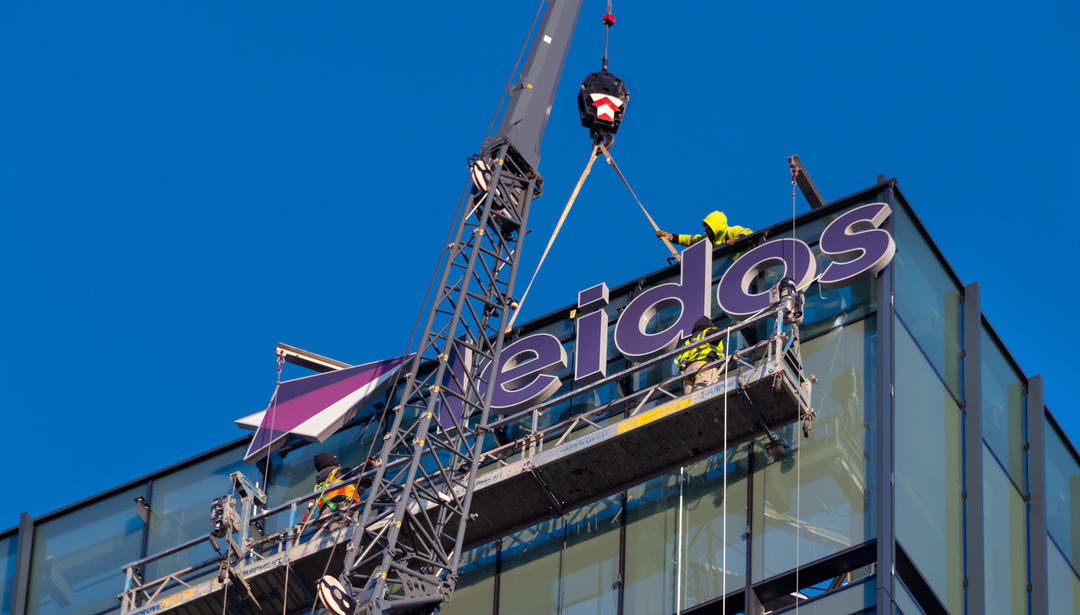 Leidos headquarters sign being added to the building with a crane