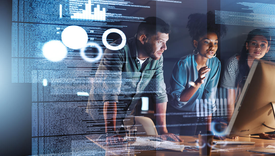 Coworkers collaborating with data on monitor screen