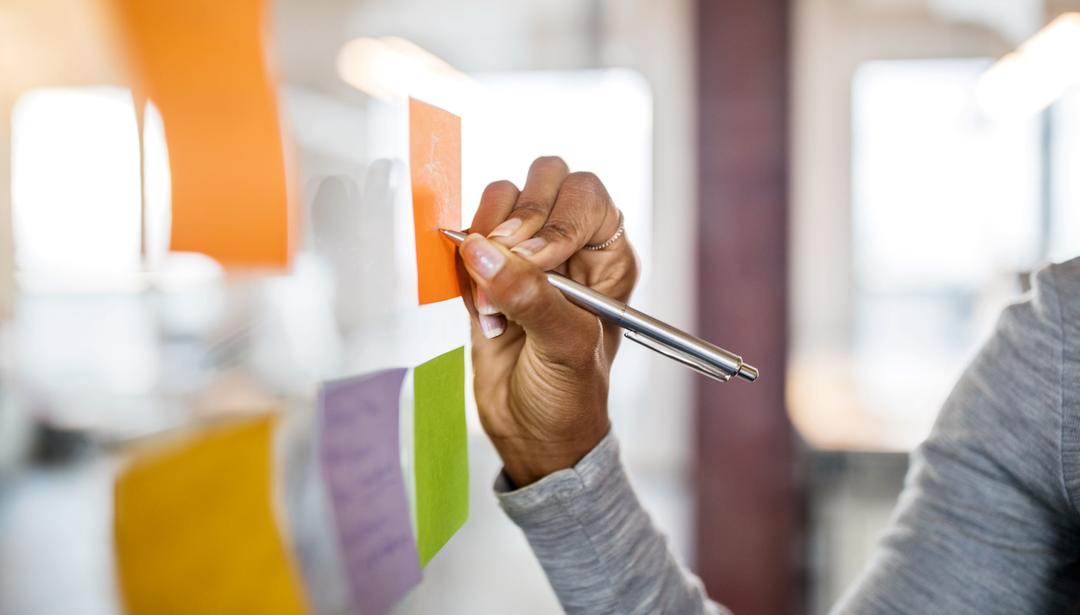 Woman hand writing on post-it note