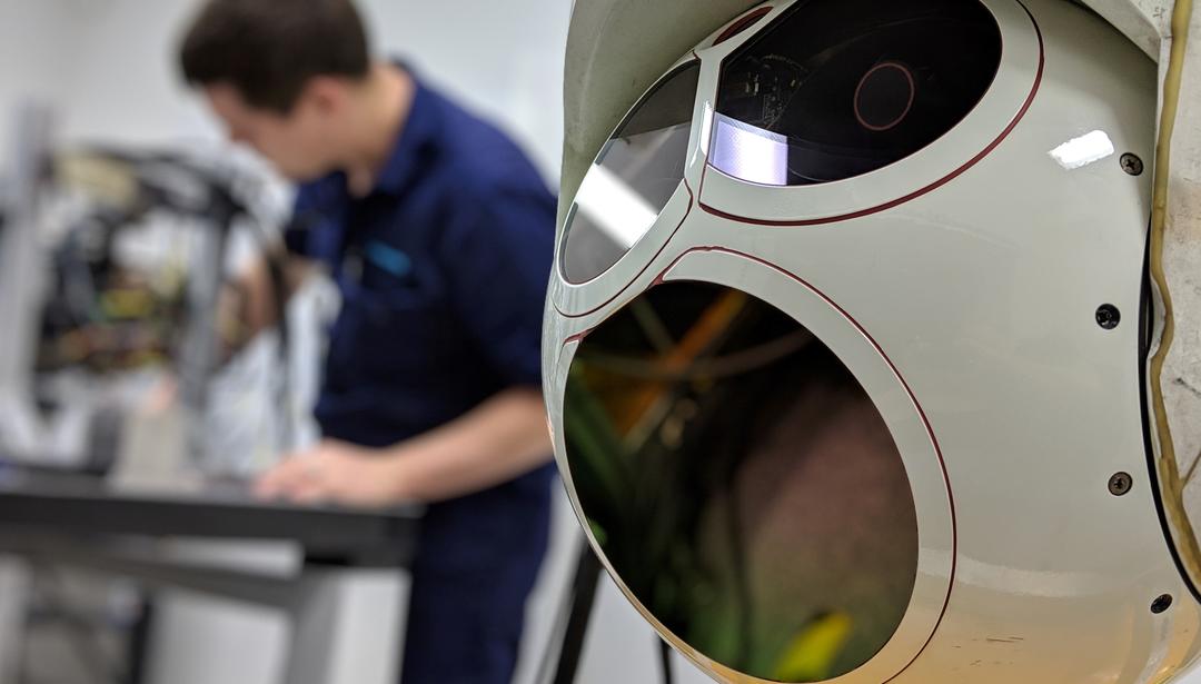 Turret camera in the foreground with man working in the background